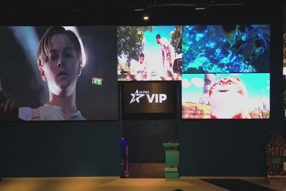 Mai multe ecrane LED cu trailere în foaierul unui cinematograf